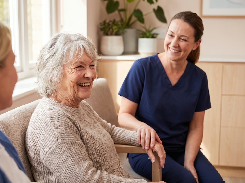 An older patient laughing with a dental nurse.